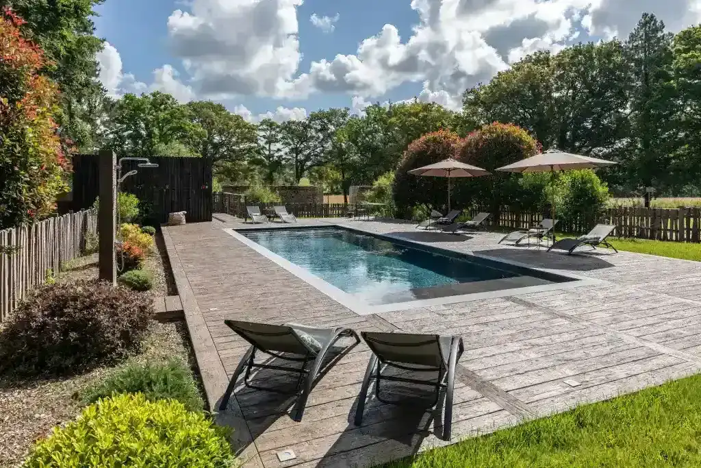 Piscine paysagée avec terrasse bois et transats dans un jardin toulousain